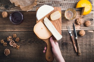 Close up hand holding cutting board  with cheese