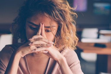 a stressed and tired young adult leans their head on their hands