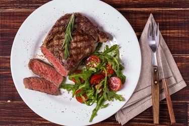 Ribeye steak with arugula and tomatoes.