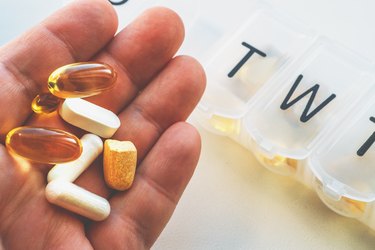 Pill box or organizer with drugs, male hand shows medications, Daily vitamins