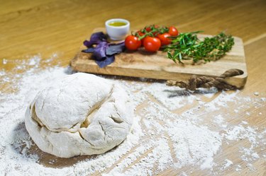 Pizza dough with cutting board with veggies