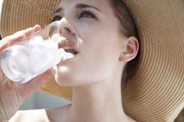 Young woman drinking from glass with ice