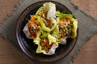 Lettuce wraps with chicken, carrot, peanuts and scallion. Stuffed iceberg lettuce leaves with chicken