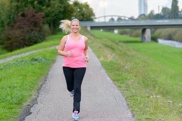 Blonde smiling woman running along river