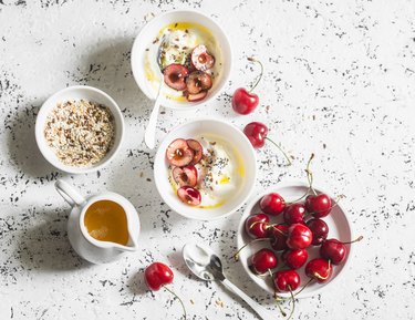 Greek yogurt with cherries and honey  on white table, top view. Flat lay. Summer breakfast or snack