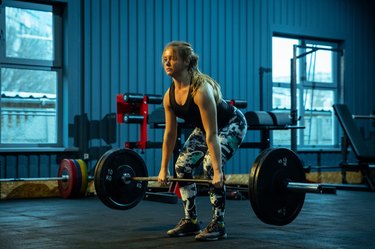 woman lifting weights in a gym for a full lower-body workout