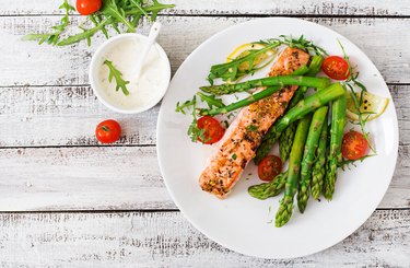 Baked salmon garnished with asparagus and tomatoes with herbs