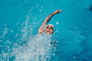 Female with tattoos swimming backstroke in a pool