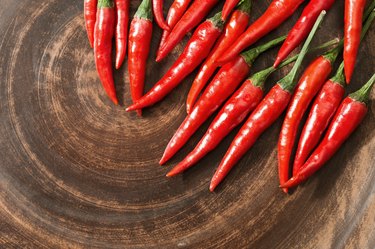 Red hot chili peppers on brown clay flat plate. Copy space. Top view. Food background.