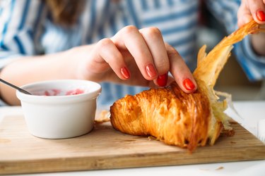 女人吃牛角包，牛角包是一种反式脂肪食物