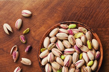 Bowl of pistachio nuts on wooden rustic table top view. Healthy food and snack. Vintage.