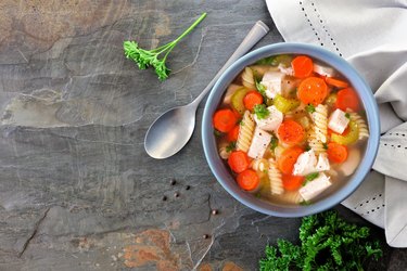 Homemade chicken noodle soup with vegetables, above on dark slate