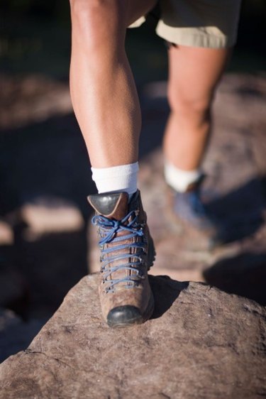close up of person's feet wearing hiking boots stepping onto a large rock