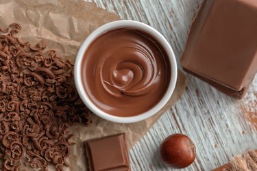 Bowl with tasty melted chocolate on wooden background