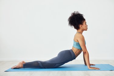 woman doing upward facing dog and practicing yoga at home