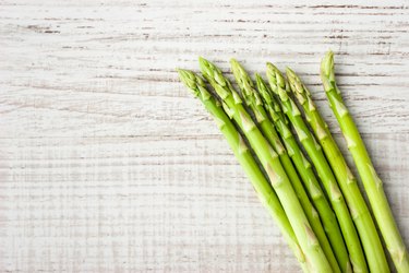 Sprigs of fresh asparagus on a wooden table.