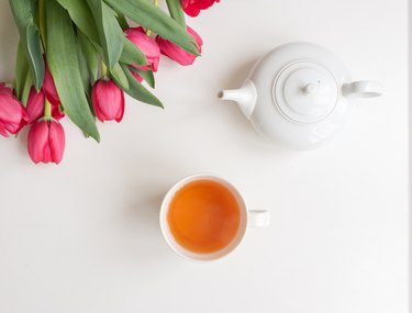 Top view of red tulips and white teapot and teacup full of Asian Slim Tea and Chinese Slim weight-loss tea