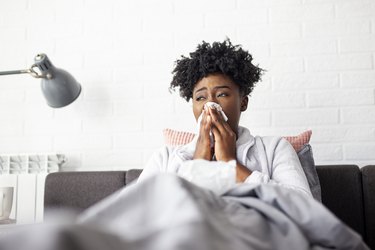 Woman lying in bed with virus and high temperature