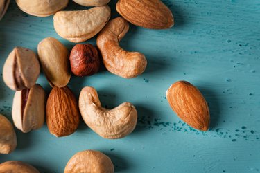 Assortment of nuts in wooden bowl on blue wooden table