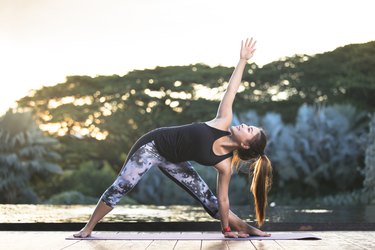 woman in black tank top and leggings stretching and practicing yoga outdoors