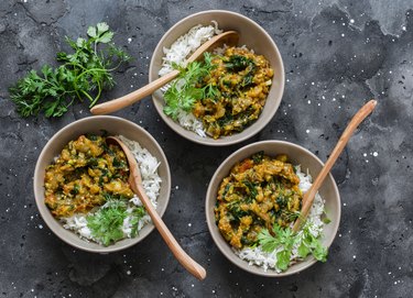 Burnt aubergine spinach vegetarian curry with rice on a dark background, top view. Indian cuisine