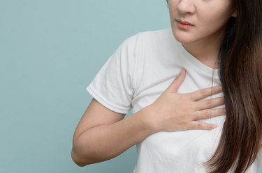 Midsection Of Woman With Chest Pain Against Blue Background