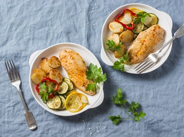 Baked chicken provencal with zucchini, squash, potatoes. Delicious healthy lunch on a blue background, top view