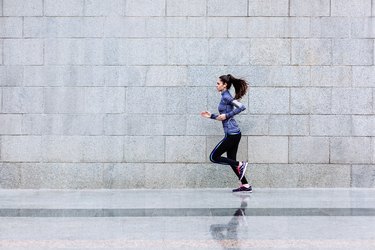 woman running during her period outside in front of a stone wall