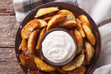 Tasty potato wedges with mayonnaise on a plate closeup. Horizontal