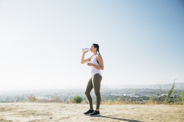 Woman taking break, drinking on hilltop