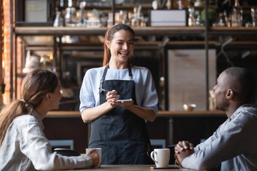 Attractive waitress laughing at African American man joke, serving customers