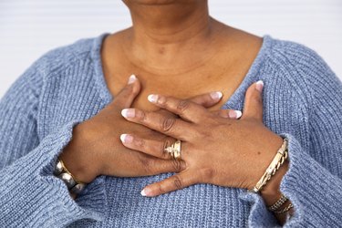 Senior African descent woman clutches chest in pain