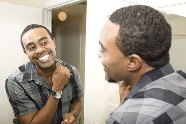 Smiling Young Man Getting Ready in front of Bathroom Mirror