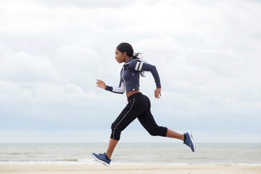 side portrait of african american woman running by the beach