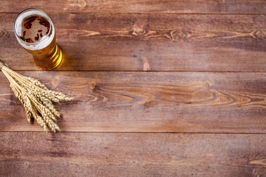 Glass of beer with wheat on a wooden table background with copy space for text. flat lay, top view
