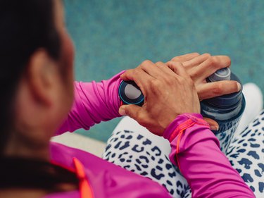 A woman dressed for exercise looking at her sports watch to help her lose body fat
