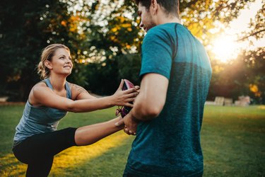 Couple assisting each other with hamstring stretches