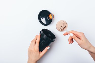 Woman's hands putting scoop of chocolate protein