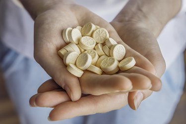 a person's hands filled with vitamin C tablets