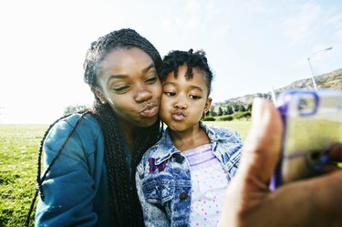 mother and daughter taking selfie outdoors