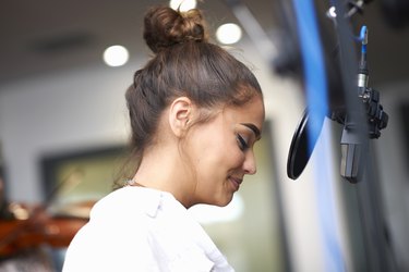 Young female college student preparing to sing in recording studio