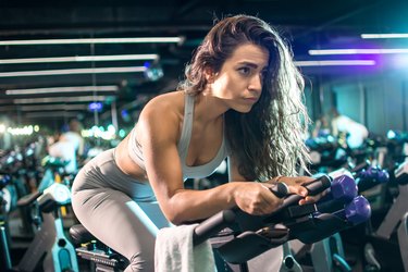 Beautiful fit woman cycling during workout on stationery bike for burning calories in the  studio.