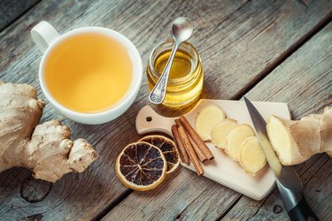 Ginger, jar of honey, tea cup on kitchen table.