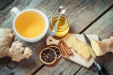 Ginger, jar of honey, tea cup on kitchen table.