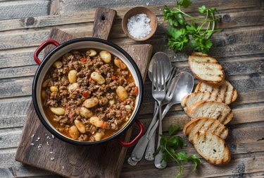 Cannellini beans beef slow-cooker stew on the wooden table, top view. Autumn, winter seasonal, healthy comfort food