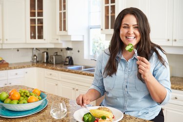 Overweight Woman Eating Healthy Meal In Kitchen