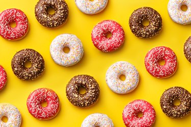 Pink, white and brown donuts in a pattern on a yellow background