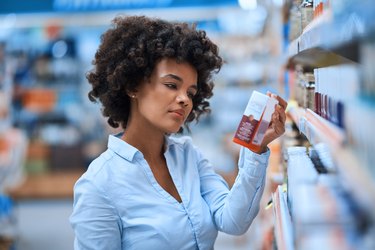 a woman looking at a box of probiotics in a health food store