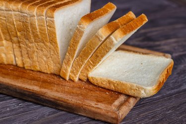 White bread sliced with slices on a wooden background for foods high in sodium