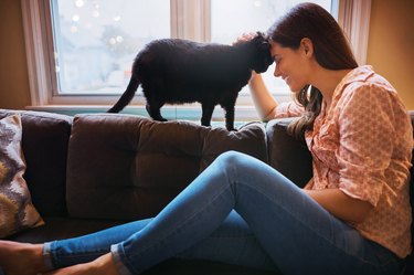 A woman sitting on the couch petting her cat to lower stress quickly